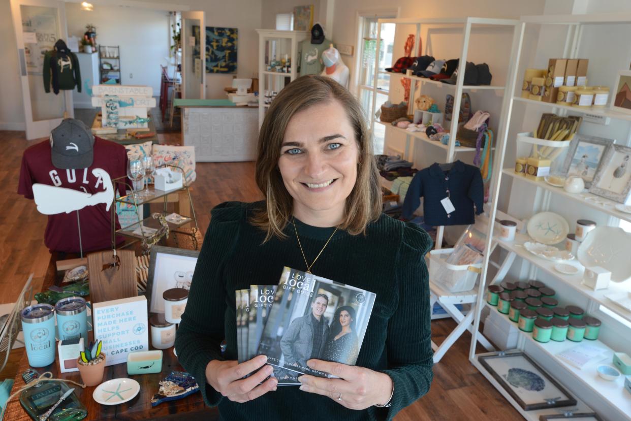 Amanda Converse poses with the 2021 edition of their gift guide at the Live Love Local store on Main Street Hyannis.