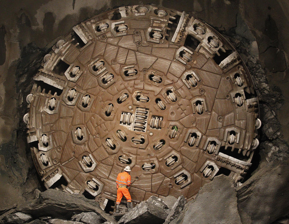 Miner stands in front of drill machine 'Sissi' after it broke through the rock at the final  section at construction site of the NEAT Gotthard Base Tunnel