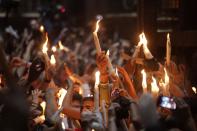 Christian pilgrims hold candles at the church of the Holy Sepulcher, traditionally believed to be the burial site of Jesus Christ, during the ceremony of the Holy Fire in Jerusalem's Old City, Saturday, April 19, 2014. The "holy fire" was passed among worshippers outside the Church and then taken to the Church of the Nativity in the West Bank town of Bethlehem, where tradition holds Jesus was born, and from there to other Christian communities in Israel and the West Bank. (AP Photo/Dan Balilty)