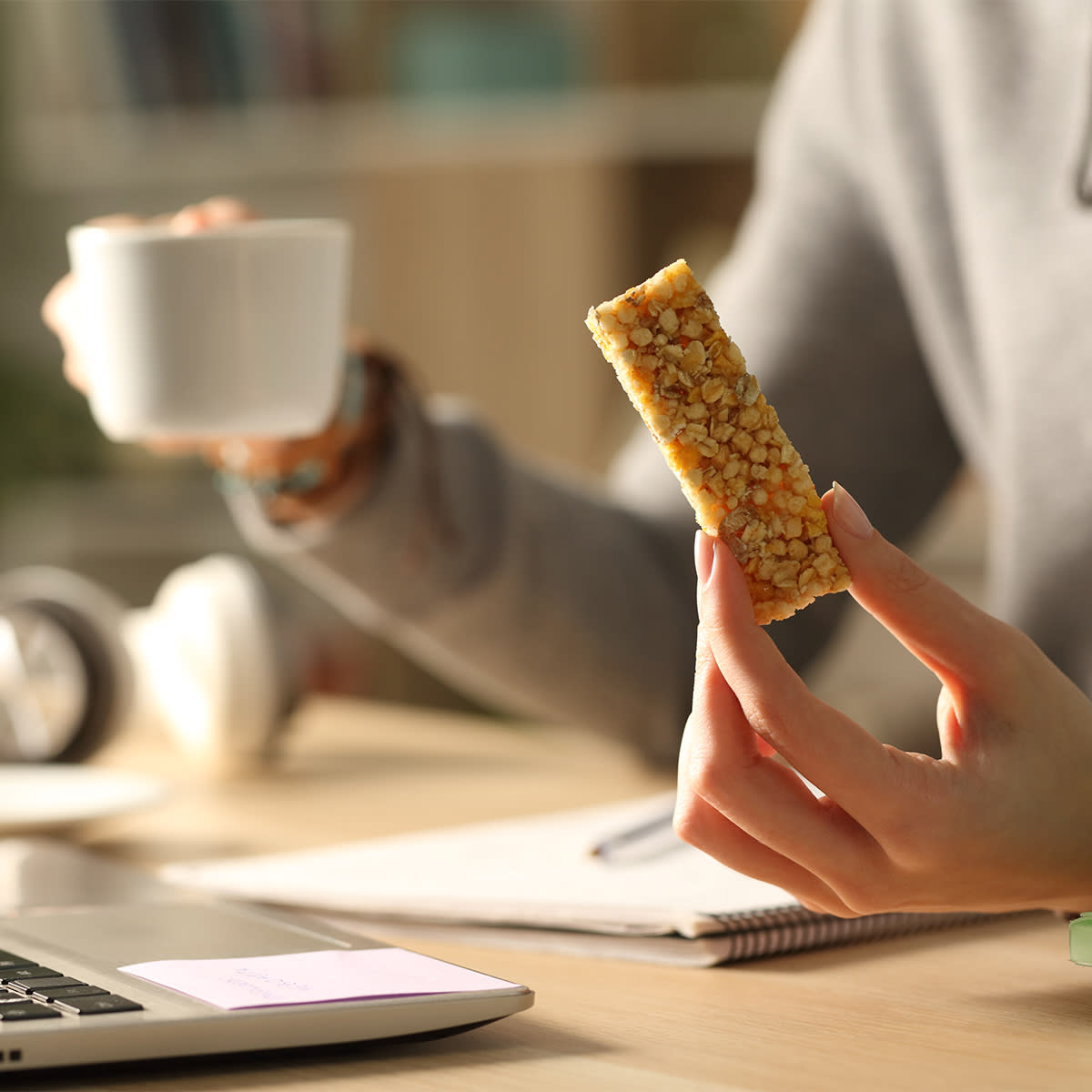 woman eating granola bar and drinking coffee