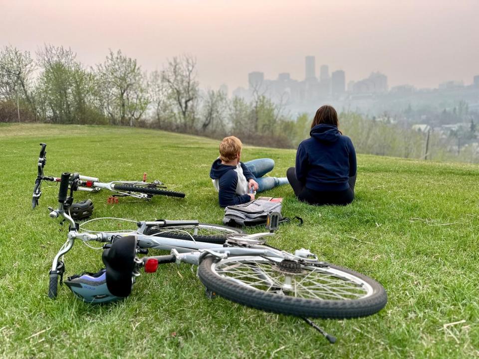 Edmontonians Nathan Kubik and Paige Wright stop at Gallagher Park for a look at the city skyline as smoke from Fort Nelson, B.C. almost 900 km away fills the air. 