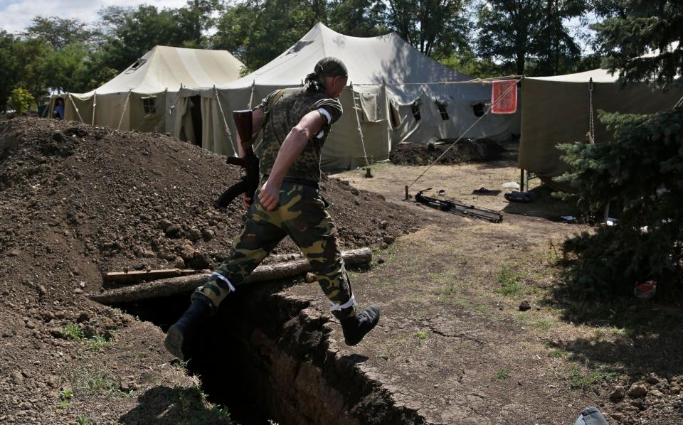 A pro-Russian rebel jumps over a trench at the Novoazovsk border crossing point, in eastern Ukraine - Sergei Grits 