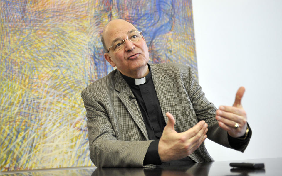 In this photo taken Tuesday, Jan. 21, 2014, church provost Christian Leibnitz speaks during an interview with the Associated Press on Nazi symbols on gravestones at a cemetary in Graz, Austria. Austrian law bans such symbols, and those displaying them face criminal charges and potential prison terms. Yet the emblems reflecting this country’s darkest chapter in history endure here, and officials here appear either unable or unwilling to do away with them. (AP Photo/Hans Punz)