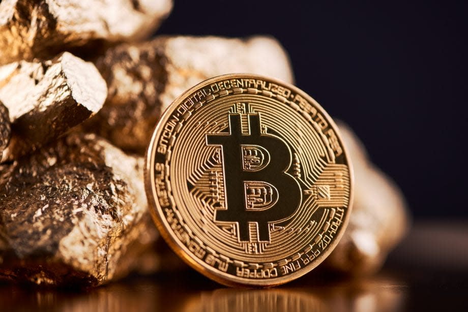 Eine Bitcoin Münze lehnt an Gold Nuggets an