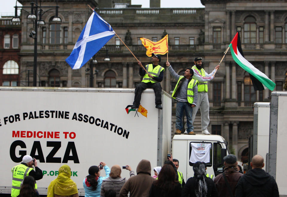 GLASGOW, SCOTLAND - FEBRUARY 20:  Rizi Mohammed, Abdul Aziz and Imran Yaqub wave flags on top of a lorry as an aid convoy stacked with aid leaves Glasgow for Gaza on February 20, 2009 in Glasgow, Scotland. The convoy will meet up with Repect MP George Galloway and his vehicles at the Rafah border before heading into Gaza.  (Photo by Jeff J Mitchell/Getty Images)