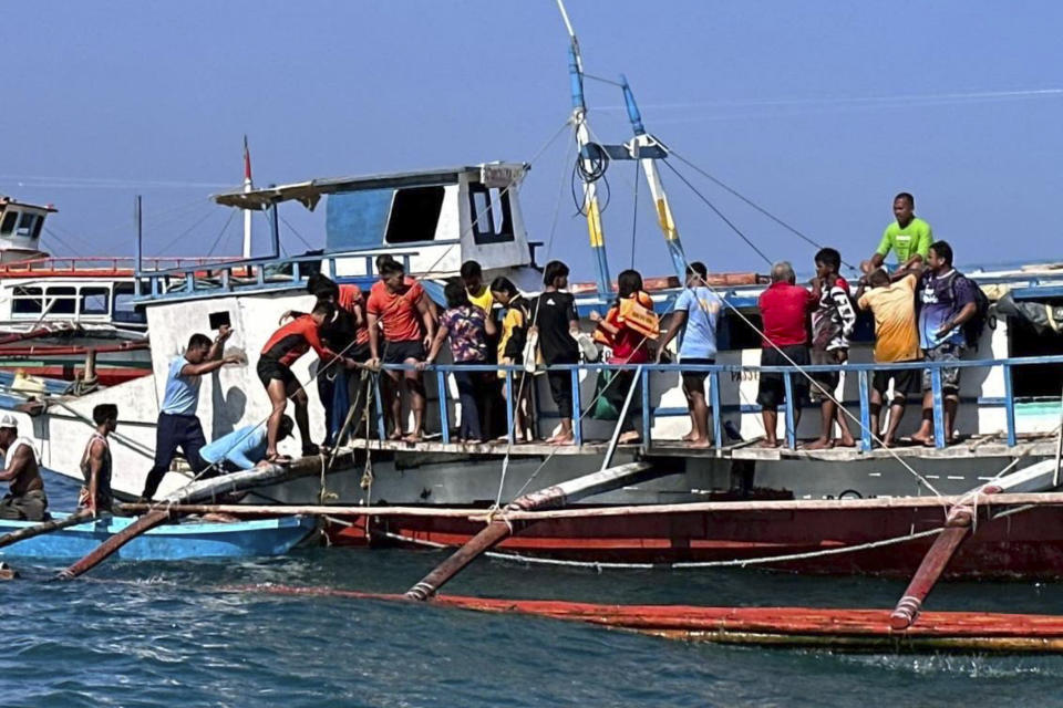 In this handout photo provided by the Philippine Coast Guard, rescuers assist passengers board a boat after a passenger ferry began to take on water in the vicinity waters off Corcuera, Romblon province, central Philippines on Saturday Aug. 5, 2023. One person died and more than 100 had to be rescued after a ferry King Sto. Nino 7 in the central Philippines struck floating debris at sea and took on water Saturday, police said. (Philippine Coast Guard via AP)