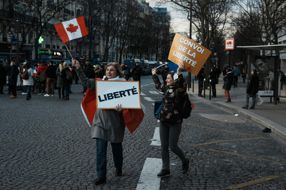 Protestors hold placards reading "Freedom", on the left, and "Freedom convoy", on the right, as they attend a gathering, in Paris, Friday, Feb. 11, 2022. Protesters angry over pandemic restrictions are driving toward Paris in scattered convoys of camper vans, cars and trucks to blockade the French capital despite a police ban. (AP Photo/Thibault Camus)