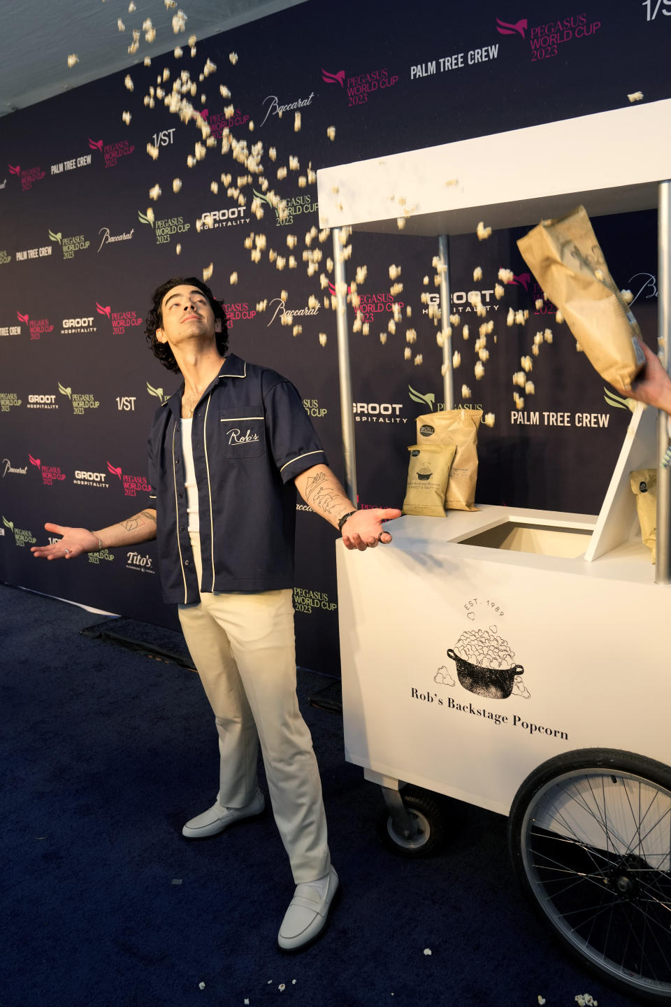 Joe Jonas poses with Rob's Backstage Popcorn as he arrives for the Pegasus World Cup Invitational horse race, Saturday, Jan. 28, 2023, at Gulfstream Park in Hallandale Beach, Fla. (AP Photo/Lynne Sladky)