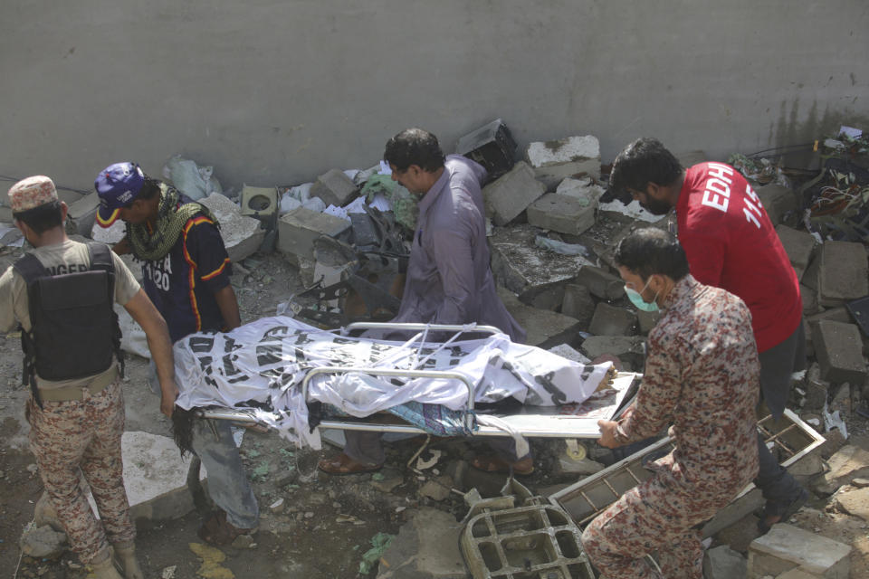 Volunteers carry the dead body of plane crash victim in Karachi, Pakistan, Friday, May 22, 2020. An aviation official says a passenger plane belonging to state-run Pakistan International Airlines carrying more than 100 passengers and crew has crashed near the southern port city of Karachi. (AP Photo/Fareed Khan)