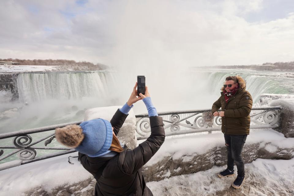 A man has his photo taken at the Horseshoe Falls in Niagara Falls, Ontario, on January 27, 2021. (Photo by Geoff Robins / AFP) (Photo by GEOFF ROBINS/AFP via Getty Images)