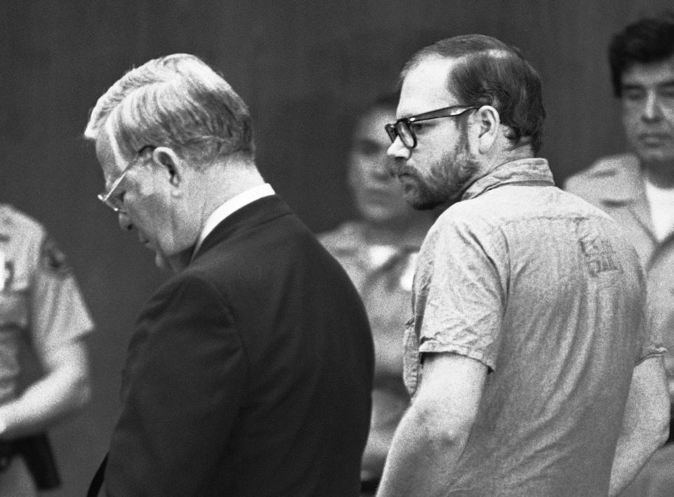 FILE - In this March 18, 1980 file photo, Roy Lewis Norris, a Redondo Beach electrician, stands in court as he listens to charges read against him in the death of five teen-aged girls in a Torrance, Calif., courtroom. Norris pleaded guilty to five counts of murder in the rape-torture of the five, as well as two counts of rape and one count of robbery in a plea bargain to avoid the death penalty. At left is his attorney Ray Legg. California officials say one of the so-called "Tool Box Killers," who preyed on teenage girls in Southern California more than 40 years ago, has died. Norris, now 72, died of natural causes on Monday, Feb. 24, 2020, at California Medical Facility. Norris had been serving a 45-years-to-life sentence. (AP Photo/Wally Fong, File)