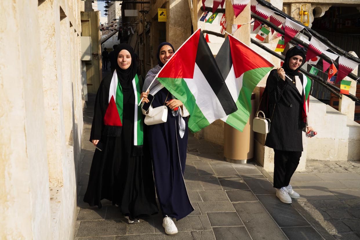 Palestinian women wave the Palestinian flag ahead of the FIFA World Cup in Doha, Qatar, Saturday, Nov. 19, 2022. (AP Photo/Jon Gambrell)