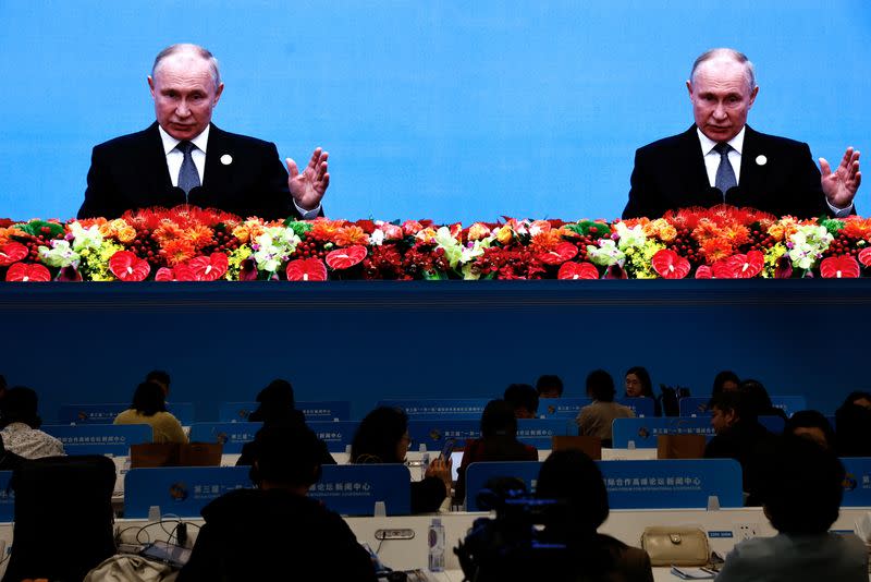 Journalists watch a giant screen broadcasting footage of Russian President Vladimir Putin at the opening ceremony of BRF in Beijing