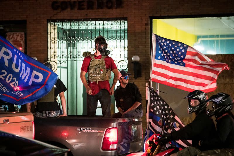 Supporters of U.S. President Donald Trump stand in flag-adorned pickup trucks during their caravan through Portland