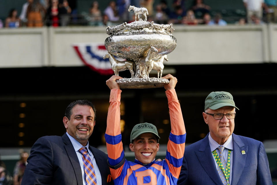 Jockey Irad Ortiz Jr. holds the August Belmont Memorial Cup after Mo Donegal won the Belmont Stakes horse race Saturday, June 11, 2022, at Belmont Park in Elmont, N.Y. With Ortiz are part-owners Mike Repole, left, and Jerry Crawford, right. (AP Photo/Frank Franklin II)