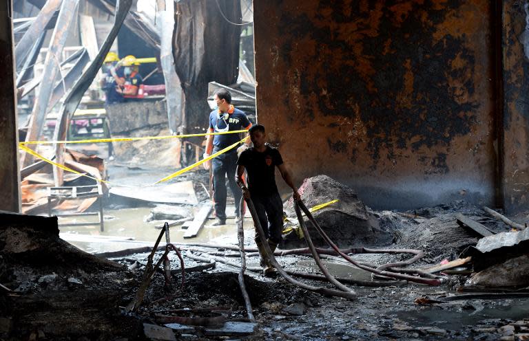 Fire investigators work in the ruins of a footwear factory in suburban Manila on May 14, 2015