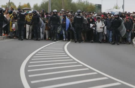 Police officers escort migrants as they make their way on foot after crossing the Croatian-Slovenian border, in Rigonce, Slovenia, October 22, 2015. REUTERS/Srdjan Zivulovic