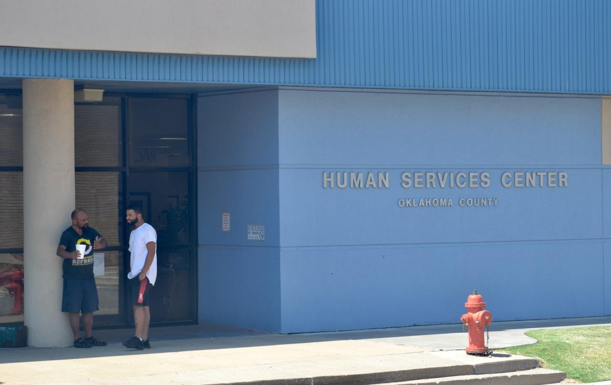 Two men talk outside a Department of Human Services office in Oklahoma City. The agency plans to open 80 new offices across the state over the next year.