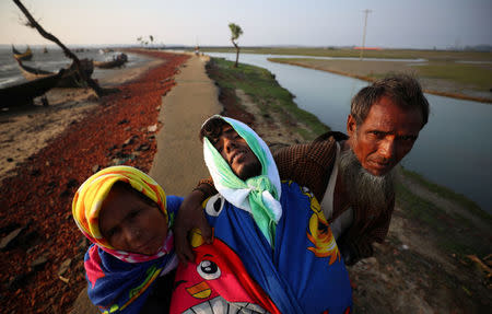 Rohingya refugees carry their sick 18-year-old son, Mohammed as they arrive at a port after crossing from Myanmar, in Teknaf, Bangladesh, October 25, 2017. REUTERS/Hannah McKay