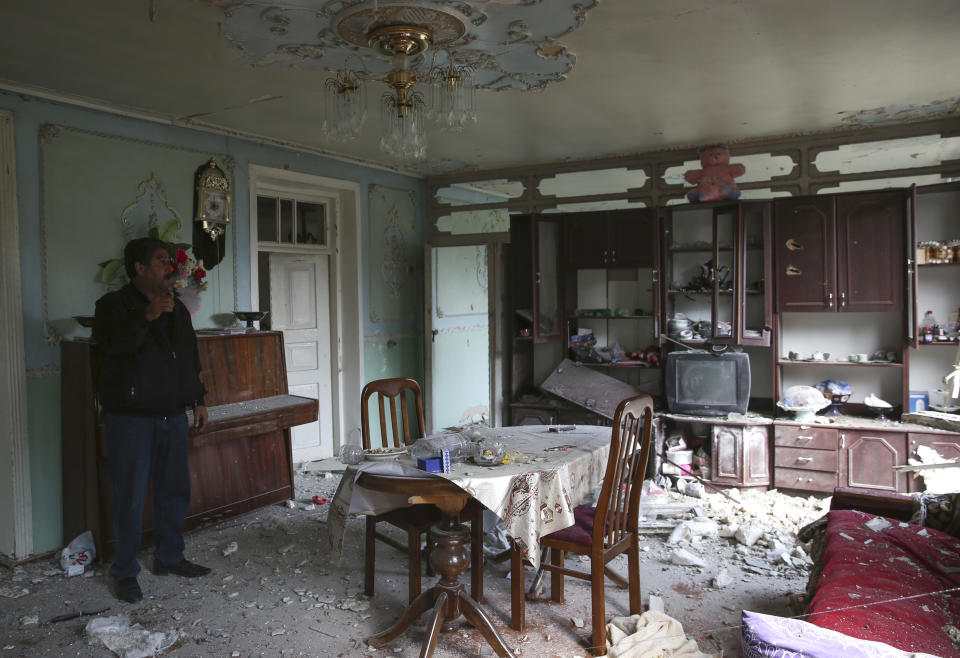 Local resident stands in an apartment building that was allegedly damaged by recent shelling during fighting over the breakaway region of Nagorno-Karabakh in Tartar region, Azerbaijan, Wednesday, Sept. 30, 2020. Leaders of Azerbaijan and Armenia brushed off the suggestion of peace talks Tuesday, accusing each other of obstructing negotiations over the separatist territory of Nagorno-Karabakh, with dozens killed and injured in three days of heavy fighting. (AP Photo/Aziz Karimov)