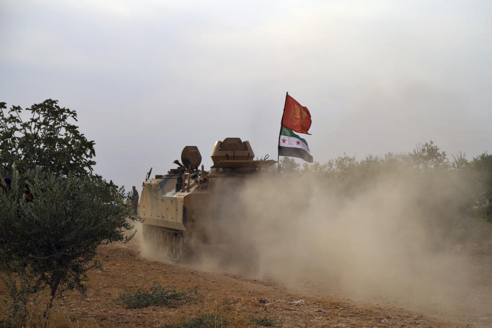 In this Monday, Oct. 14, 2019 photo, Turkey-backed Syrian opposition fighters move in an armored vehicle in Syria's northern region of Manbij. Syrian state media said Tuesday that government forces have entered the center of the once Kurdish-held northern town of Manbij and raised the national flag. (AP Photo)