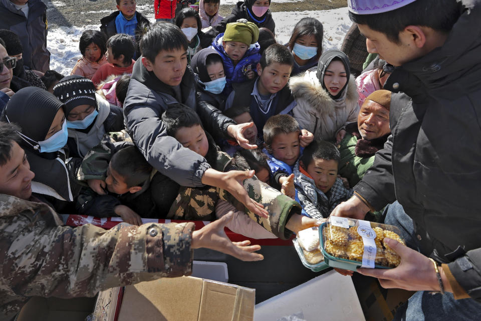 Quake victims scramble to get snack foods from a volunteer at a temporary settlement in Chenjiacun village in Jishishan county in northwest China's Gansu province on Wednesday, Dec. 20, 2023. Hundreds of temporary housing units were being set up in northwest China on Thursday for survivors of an earthquake, according to state media reports. (Chinatopix Via AP)