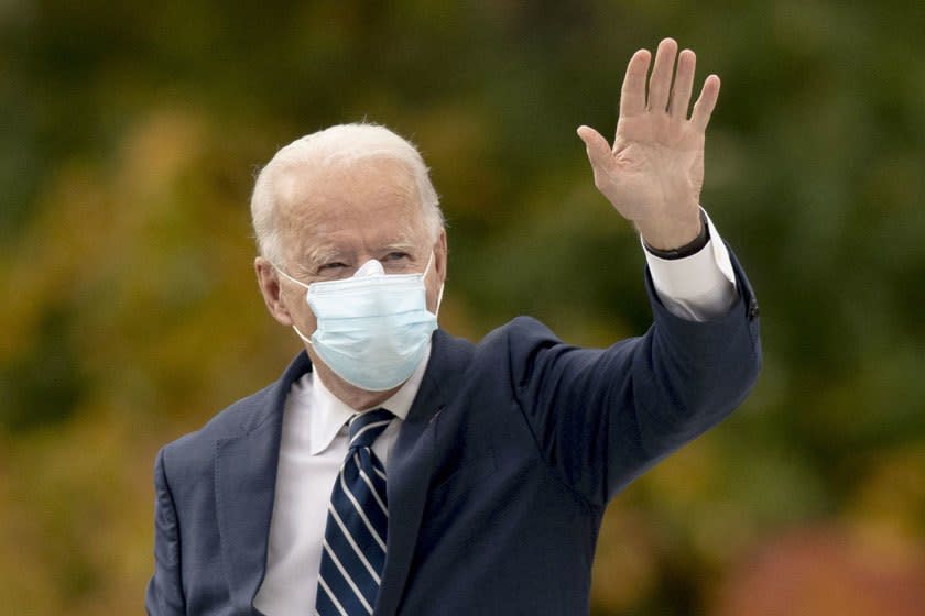 Joe Biden waving while wearing a blue face mask