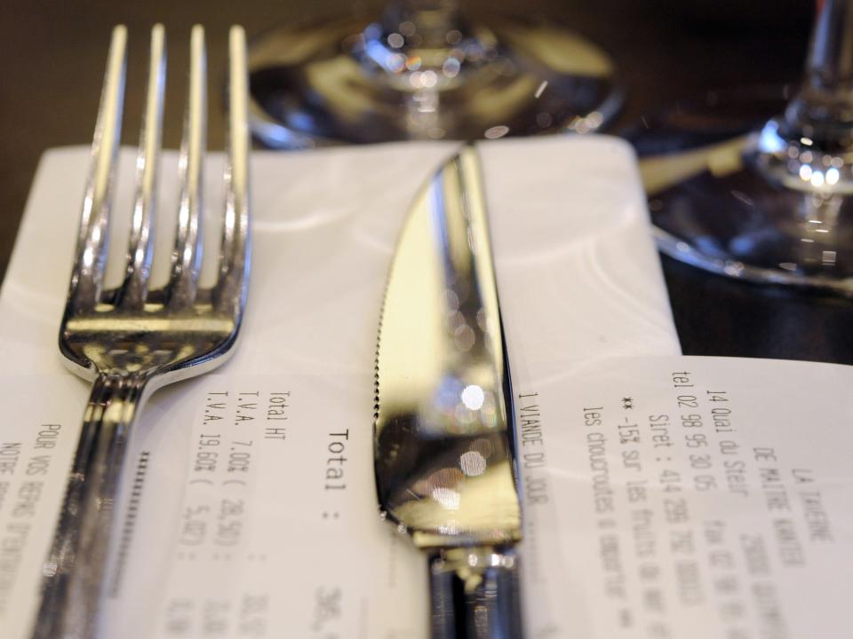 A fork and knife resting on a restaurant bill.