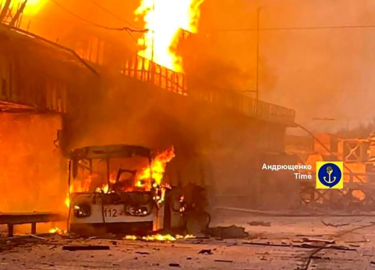 In this photo provided by Petro Andryuschenko, the adviser of the head of Mariupol city's administration, burning trolleybus is seen on the damp of hydroelectric power station after Russian attacks in Dnipro, Ukraine on Friday (AP)