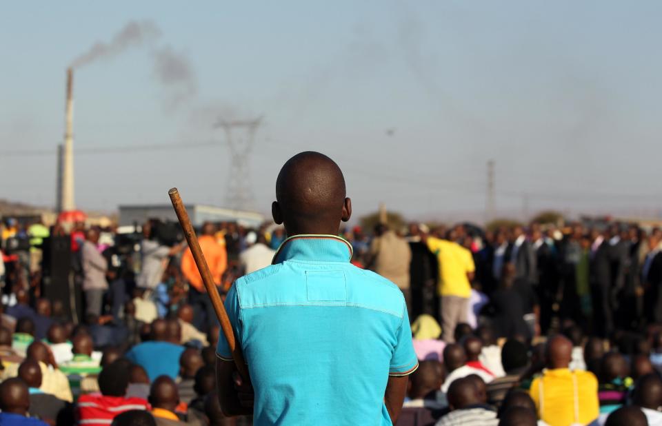 A mine worker holding a stick as government officials address them at the Lonmin mine near Rustenburg, South Africa, Tuesday, Aug. 21, 2012. Miners Workers trickled in Tuesday at the Lonmin platinum mine where 44-people have died in a wildcat strike, as South Africa urged the company to suspend an ultimatum to return to work. (AP Photo/Themba Hadebe)