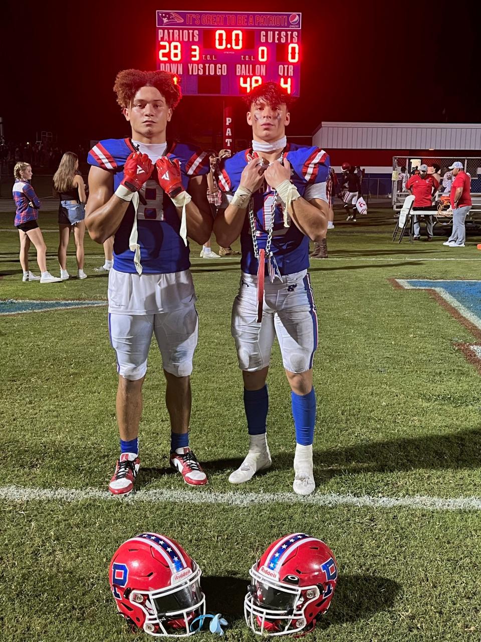Pace senior athlete Xakery Wiedner and junior quarterback pose for a photo in front the scoreboard following the team's 28-0 victory against Crestview on Sept. 15, 2023 from Pace High School.
