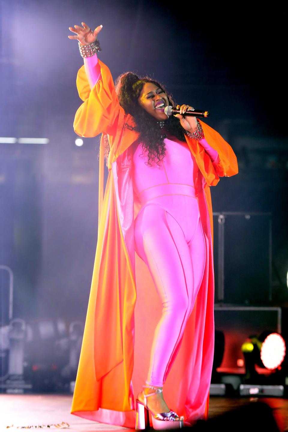 Jazmine Sullivan in a pink jumpsuit and orange cape