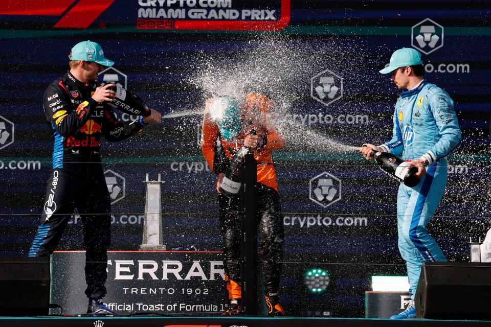 Runner-up Max Verstappen (left) and third-place finisher Charles Leclerc (right) spray champagne on race winner Lando Norris after Sunday's Miami Grand Prix.