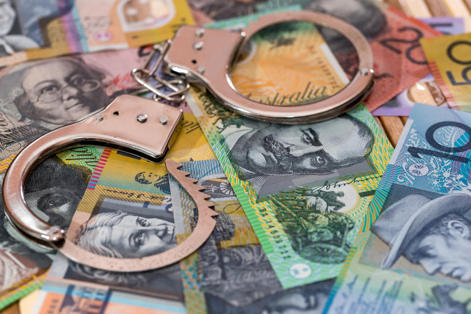 Handcuffs laying on top of a pile of Australian bank notes