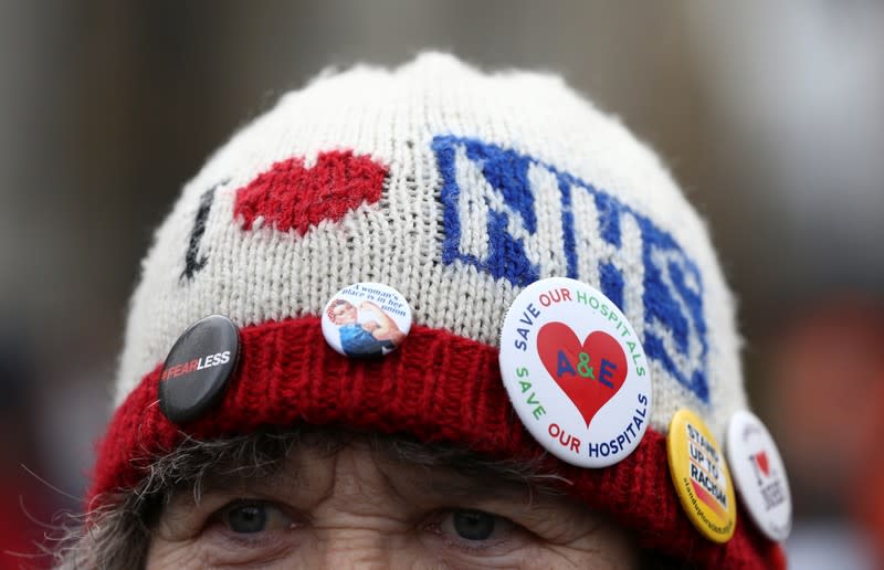 A woman wears a hat covered in badges during a demonstration to demand more funding for Britain's National Health Service (NHS), in London