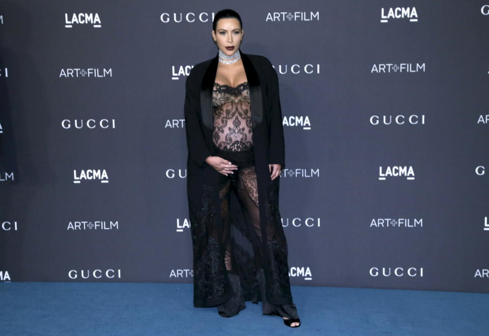 A pregnant Kim Kardashian wears a see through lace outfit with a long black coat. (REUTERS)