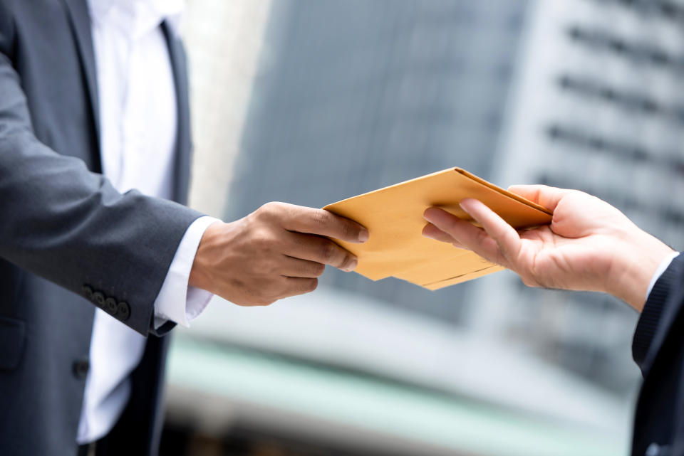 Two hands exchanging an envelope