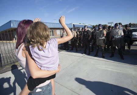 A mother and daughter raise their hands in front of riot police while protesting the shooting death of teenager Michael Brown, in Ferguson, Missouri August 13, 2014. REUTERS/Mario Anzuoni