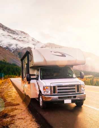 A RV on the road in a mountain setting.