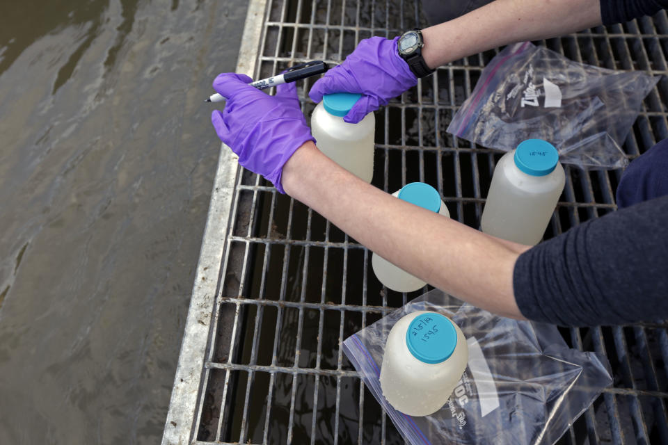 In this Wednesday, Feb. 5, 2014 photo, Amber Skiles, a contractor with the Environmental Protection Agency labels water samples from the Dan River as state and federal environmental officials continued their investigations of a spill of coal ash in Eden, N.C. Over the last year, environmental groups have tried three times to use the federal Clean Water Act to force Duke Energy to clear out leaky coal ash dumps. Each time, the N.C. Department of Environment and Natural Resources has effectively halted the lawsuit by intervening at the last minute to assert its own authority to take enforcement action. In two cases, the state has proposed modest fines but no requirement that the nation’s largest electricity provider actually clean up the coal ash ponds. The third case is pending. (AP Photo/Gerry Broome)