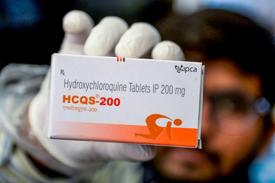 A pharmacist displaying a box of anti-malarial drug hydroxychloroquine.