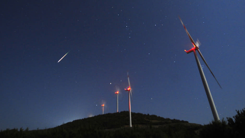 A meteor streaks across the sky during the Perseid meteor shower at a windmill farm near Bogdanci,.