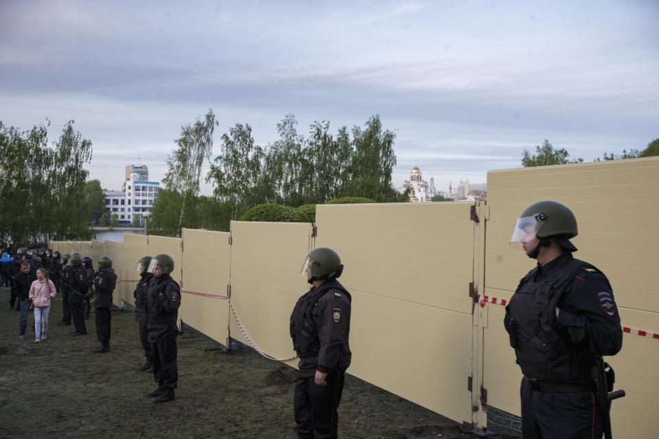 Police officers stand in front of a new built fence during a protest against plans to construct a cathedral in a park in Yekaterinburg, Russia, Wednesday, May 15, 2019. Hundreds of riot police have surrounded a park in Russia's fourth-largest city before what's expected to be a third consecutive day of protests against building a new cathedral. (AP Photo/Anton Basanayev)