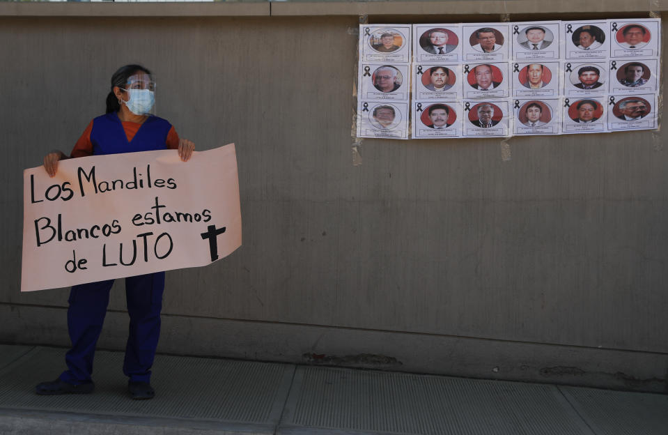 A health worker holds a sign that reads in Spanish: "The white aprons, we're in mourning" during a protest outside Petrolero Obrajes Hospital in La Paz, Bolivia, Wednesday, Jan. 27, 2021. Health workers want Bolivia's President Luis Arce to declare a quarantine to reduce the contagion of COVID-19 that has sickened doctors and filled hospitals' intensive care units. (AP Photo/Juan Karita)