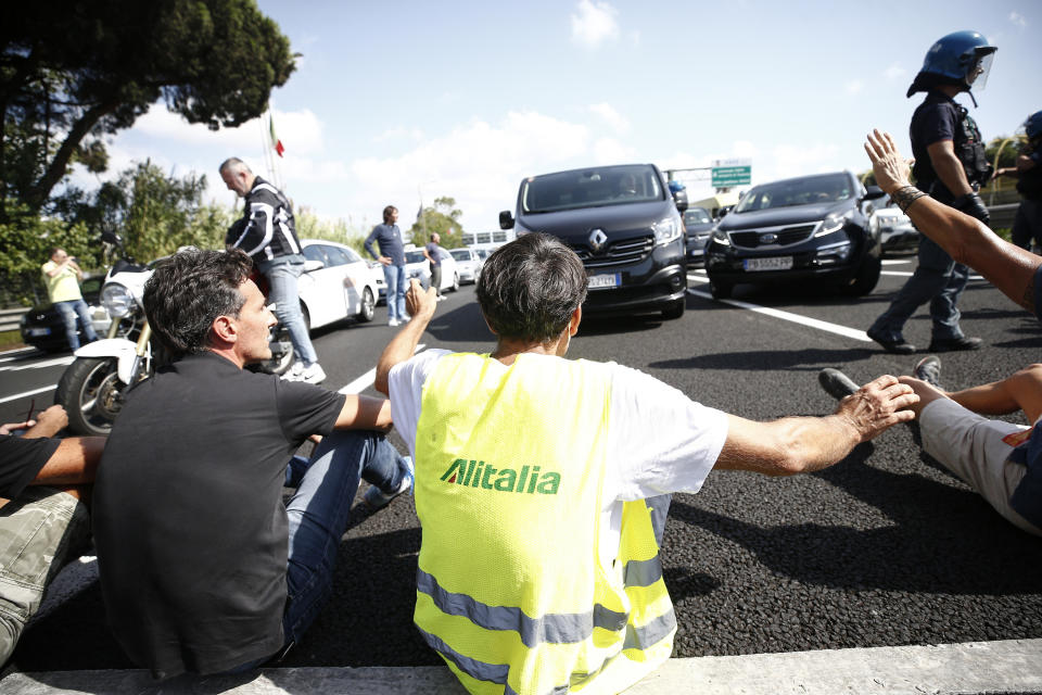 Alitalia workers block the highway leading to the Rome Leonardo Da Vinci international airport, as they stage a protest in Fiumicino, Friday, Sept. 24, 2021. Alitalia, which has been in the red for more than a decade, is due to formally exit the airline market next month and be replaced by a new national carrier ITA, or Italy Air Transport. The European Commission has given the go-ahead to a 1.35 billion euro ($1.58 billion) injection of government funding into the new airline, but ITA is only planning to hire around a quarter of the estimated 10,000 Alitalia employees.(Cecilia Fabiano/LaPresse via AP)