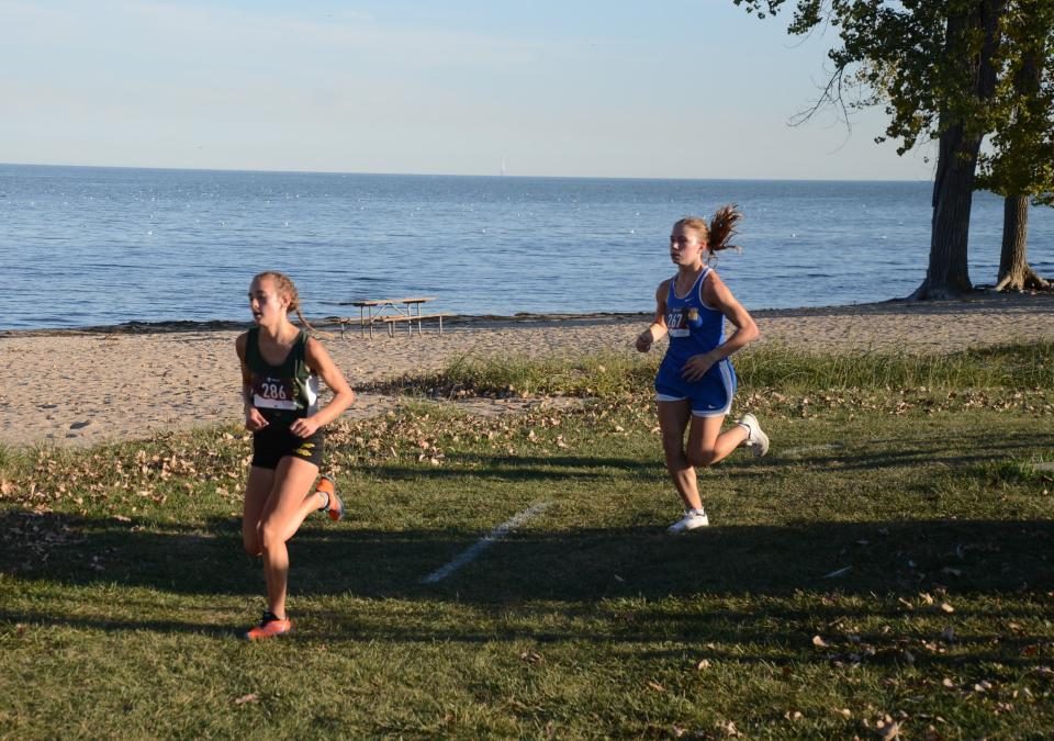 Bella LaFountain of St. Mary Catholic Central runs ahead of Jefferson’s Jenna Pilachowski in the Huron League jamboree at Sterling State Park Tuesday.