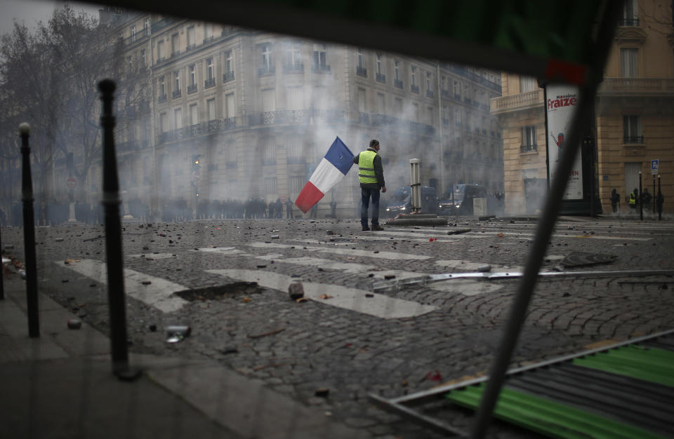 A demonstrators stands alone with a French flag during clashes Saturday, Dec. 8, 2018 in Paris. (Photo: Rafael Yaghobzadeh/AP)