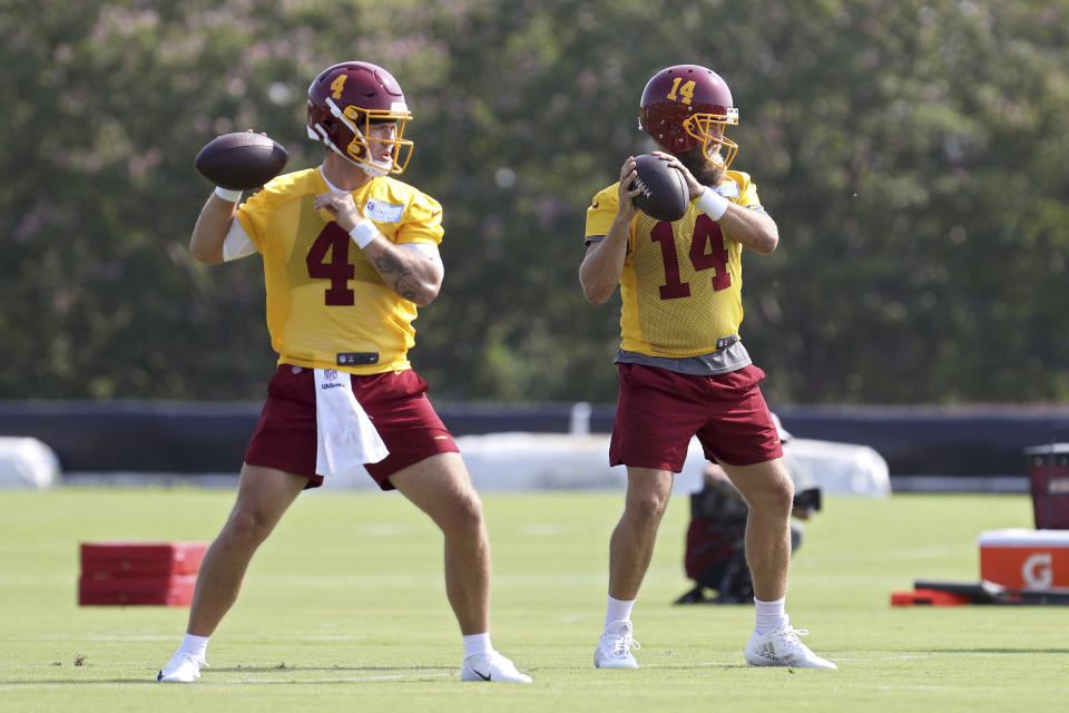 Washington Football Team quarterbacks Taylor Heinicke (4) and Ryan Fitzpatrick (14) throw passes during NFL football practice in Richmond, Va., Wednesday, July 28, 2021. (AP Photo/Ryan M. Kelly)