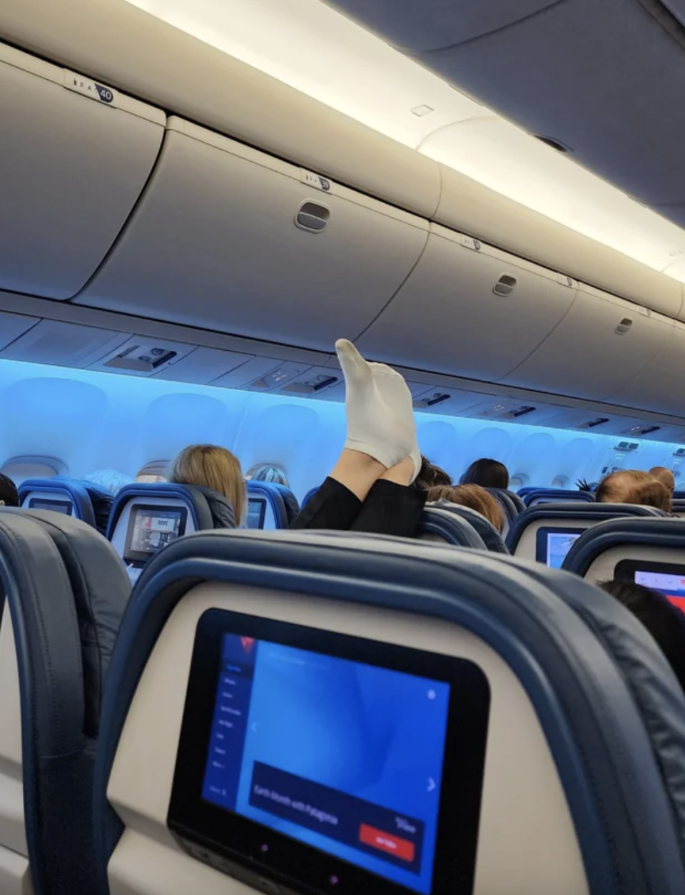 a person's feet on the seat of an airplane