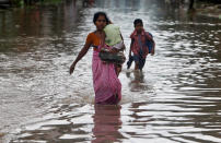 <p>A schoolboy and a woman carrying a child wade through a flooded road after heavy rains in Agartala, India, June 1, 2017. (Jayanta Dey/Reuters) </p>